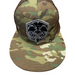 Camouflage baseball cap with a black and white logo on a wooden surface