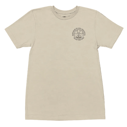 A cream-colored short-sleeve t-shirt with a circular graphic on the left chest, laid flat on a gray wood plank floor. A person's feet wearing black flip-flops are visible at the bottom edge of the frame.
