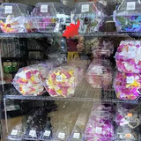 Display of floral arrangements in plastic bags with price tags in a store setting.